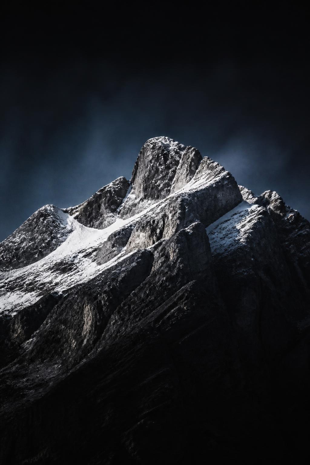 Montanha escura com picos nevados, símbolo de escala e conquista